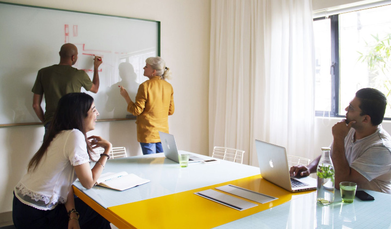 office meeting, people listening and writing notes on a white board