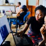 a female coworker explaining something on laptop to her coworker