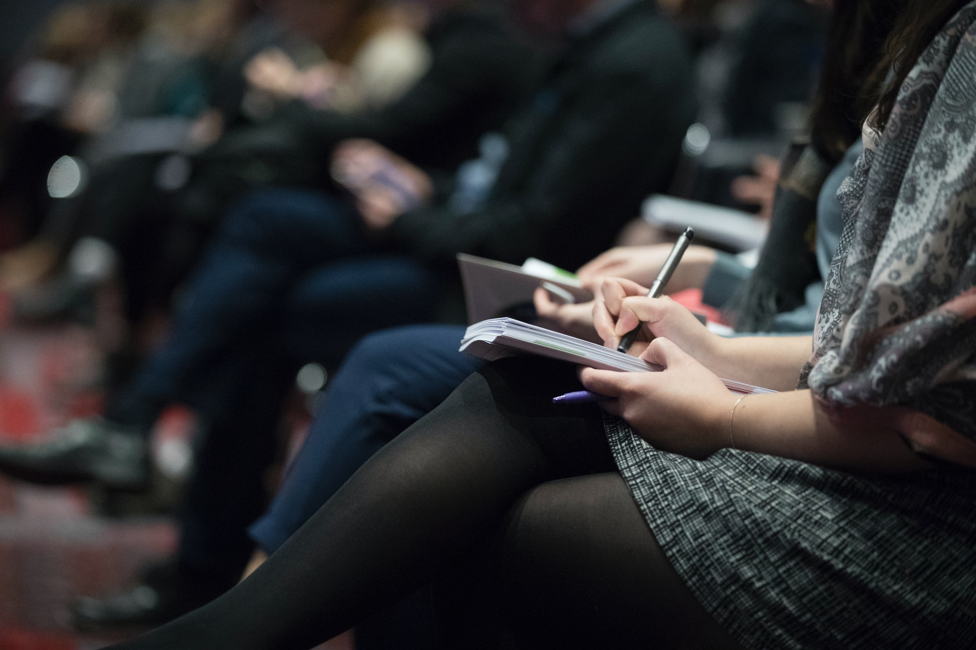 people sitting at an event and writing notes
