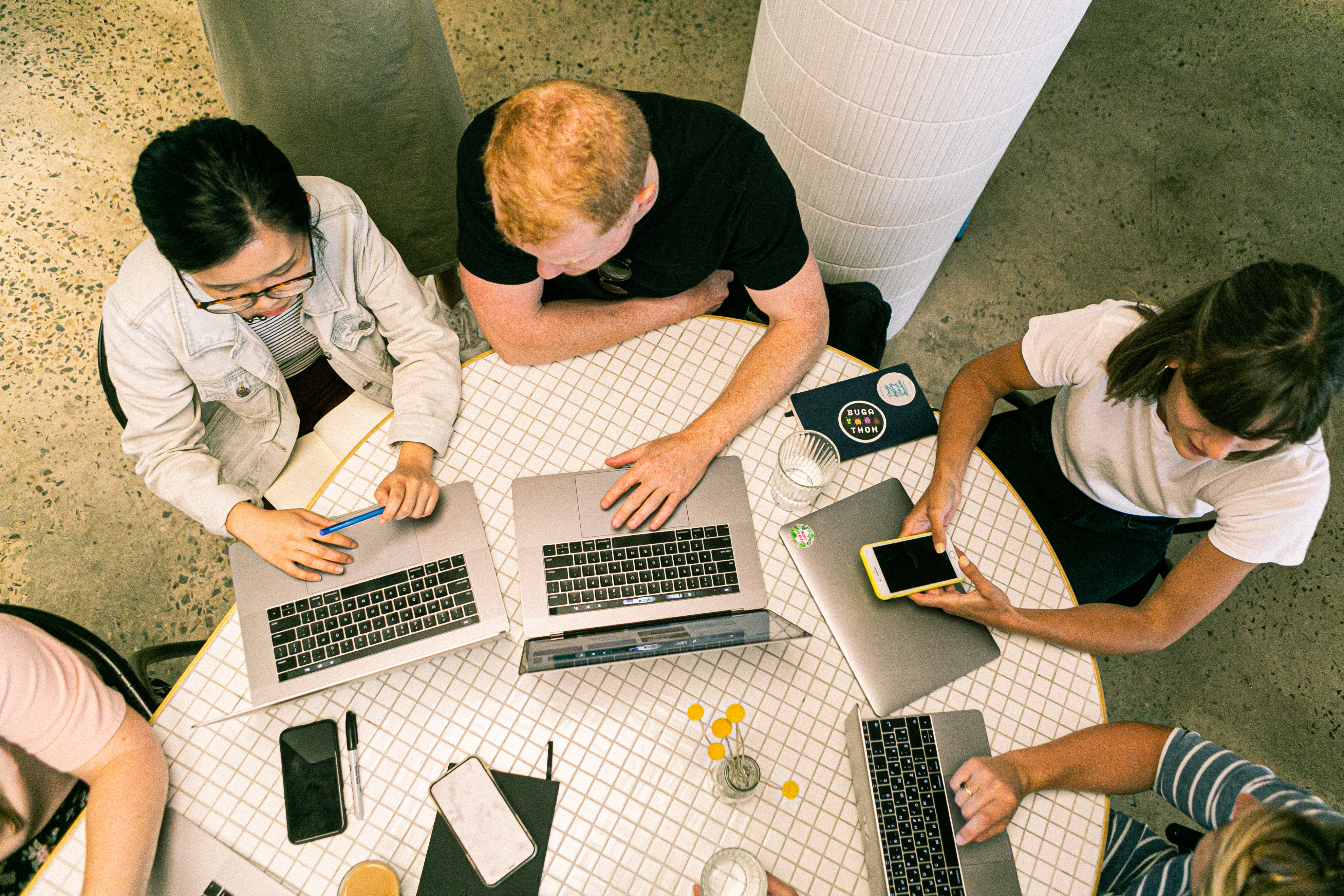 people sitting in a circle around a table with laptops