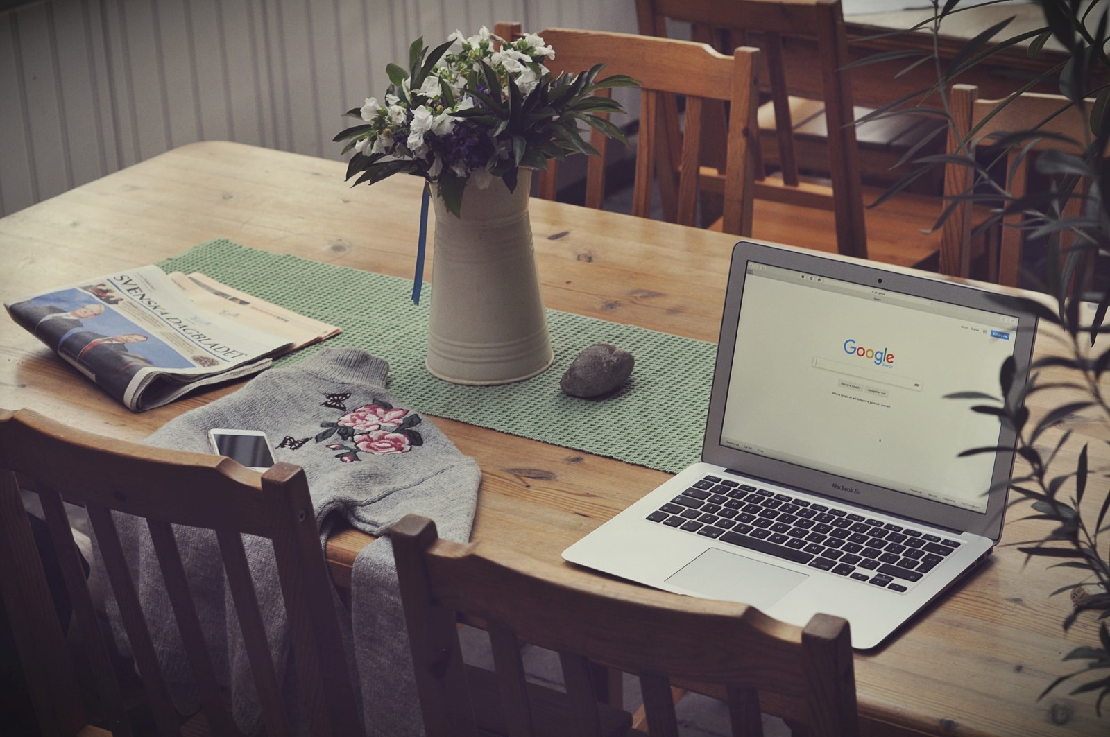 laptop, flowers and newspapers on table