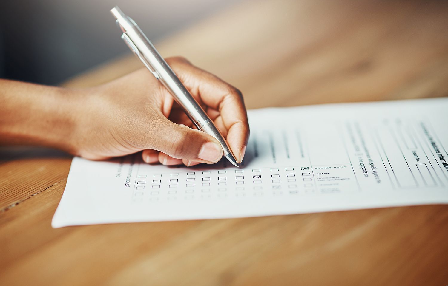 Cropped shot of a woman filling in some paperwork at a desk