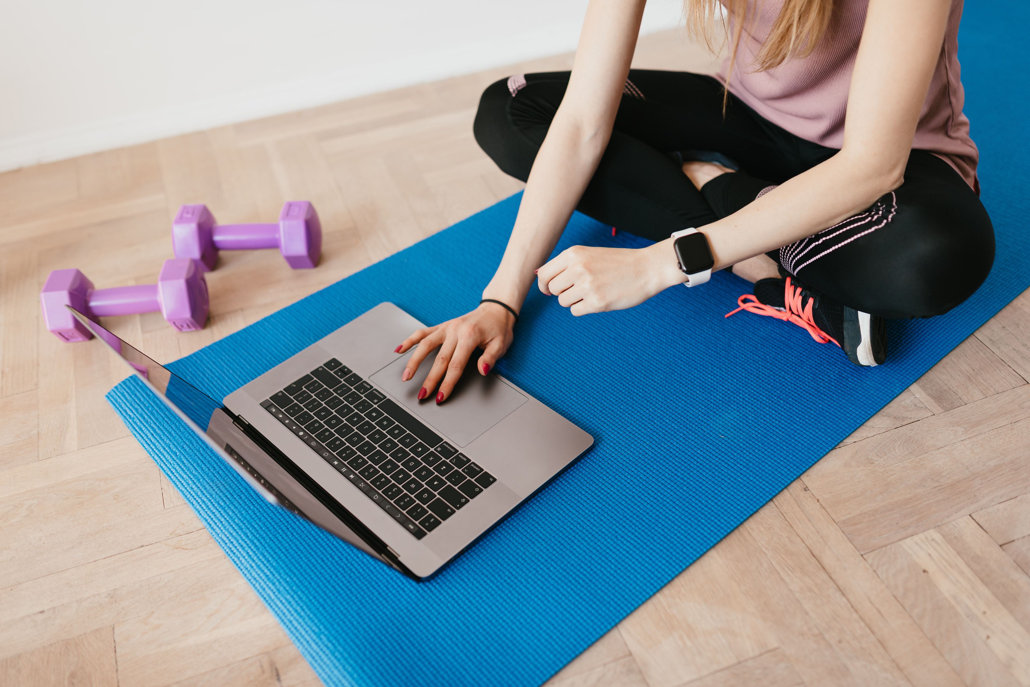 woman typing on laptop on a yoga mat