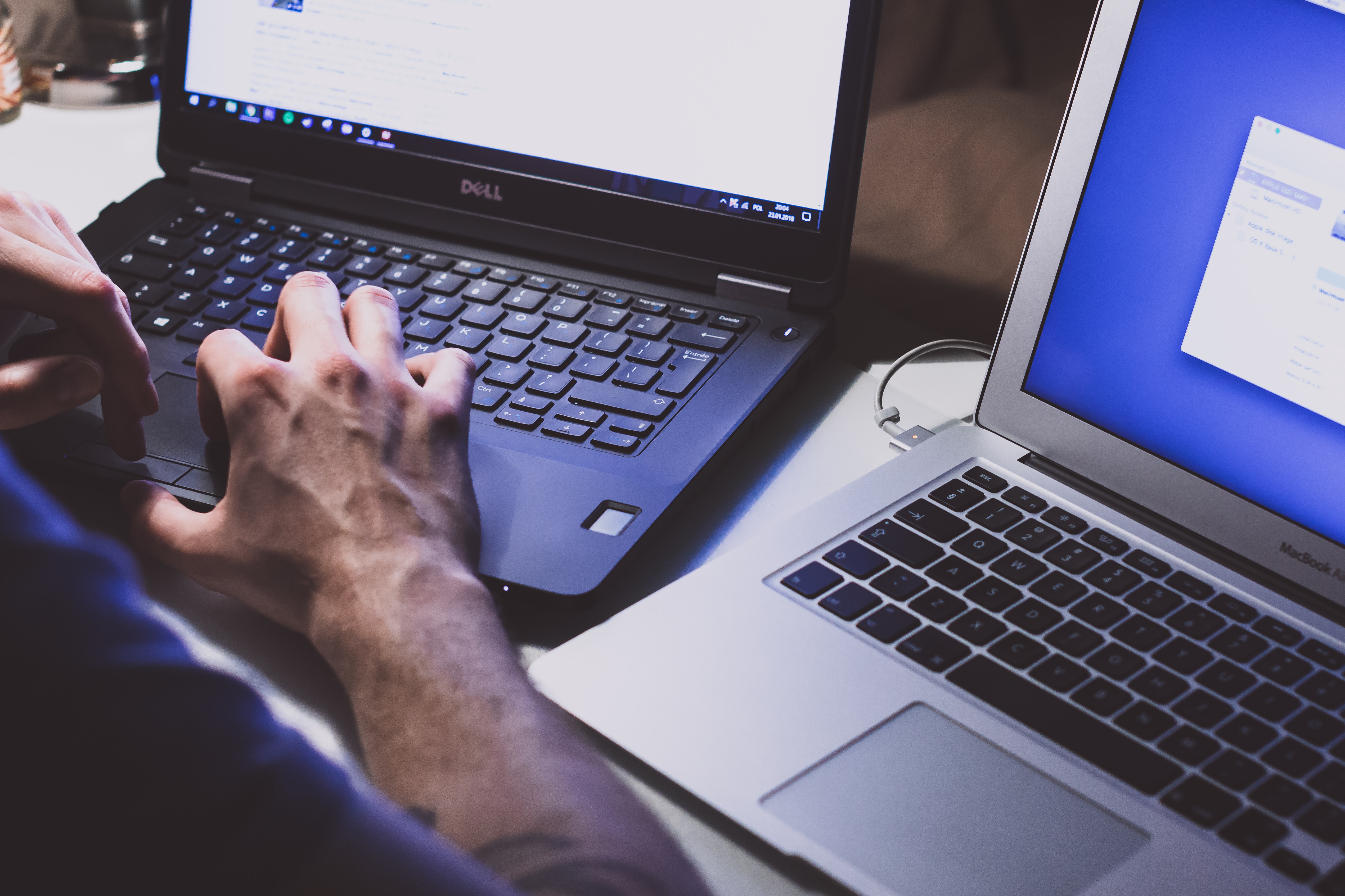 man working on two laptops