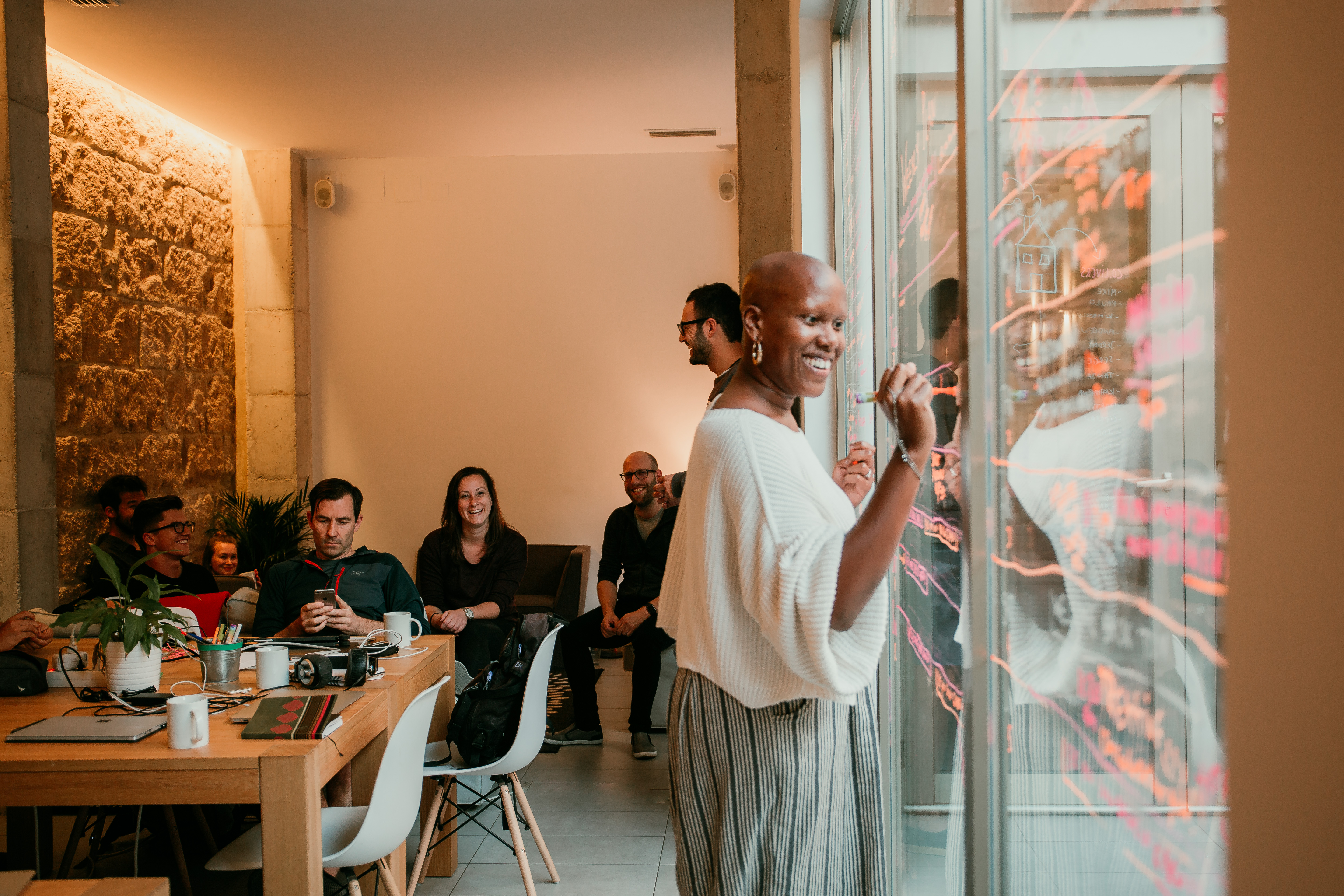 people working in a coworking space, woman writing on glass wall