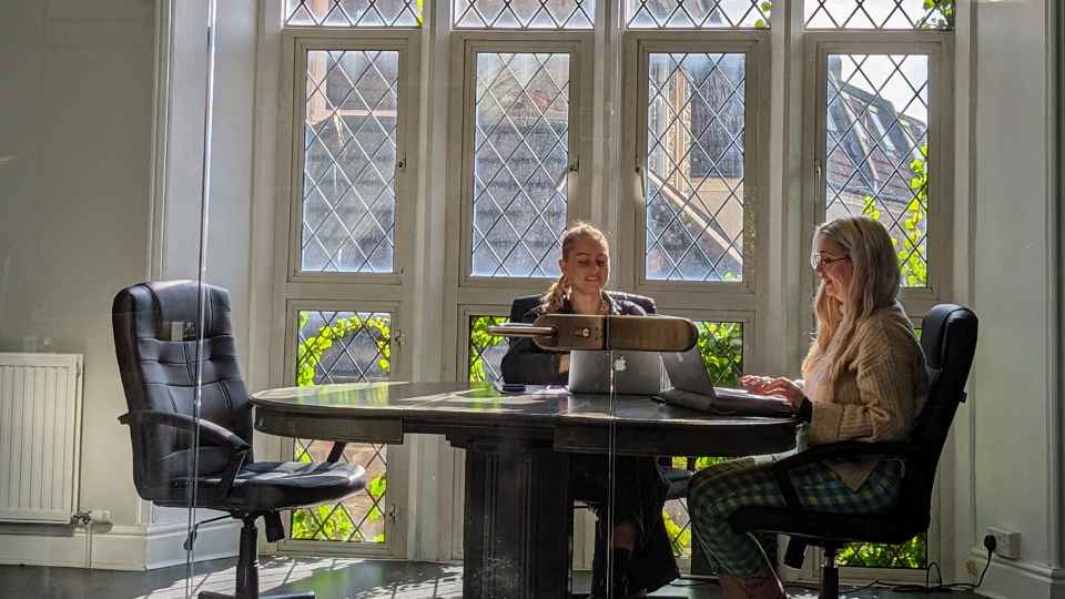 two women working in office with laptops