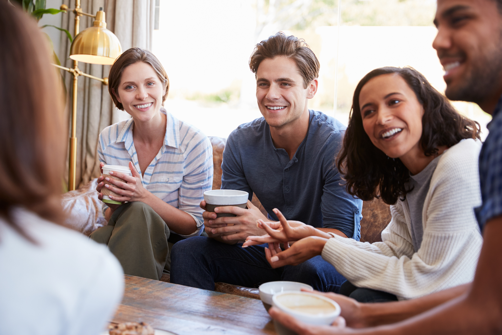 Friends relaxing around a table at a coffee shop, close up