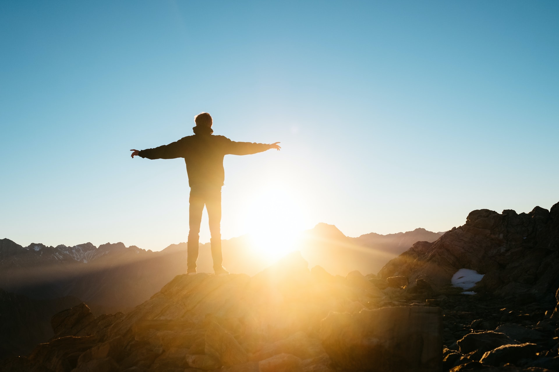 man standing on cliff on a sunset