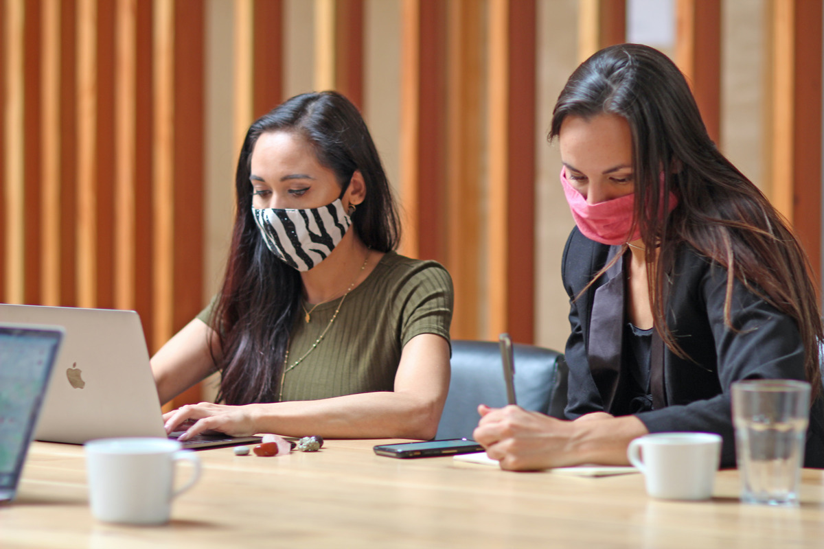 two women with masks working from a coworking office