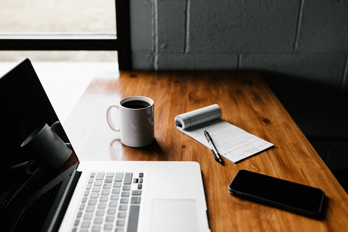 a tablet, notebook, coffee and smartphone on table