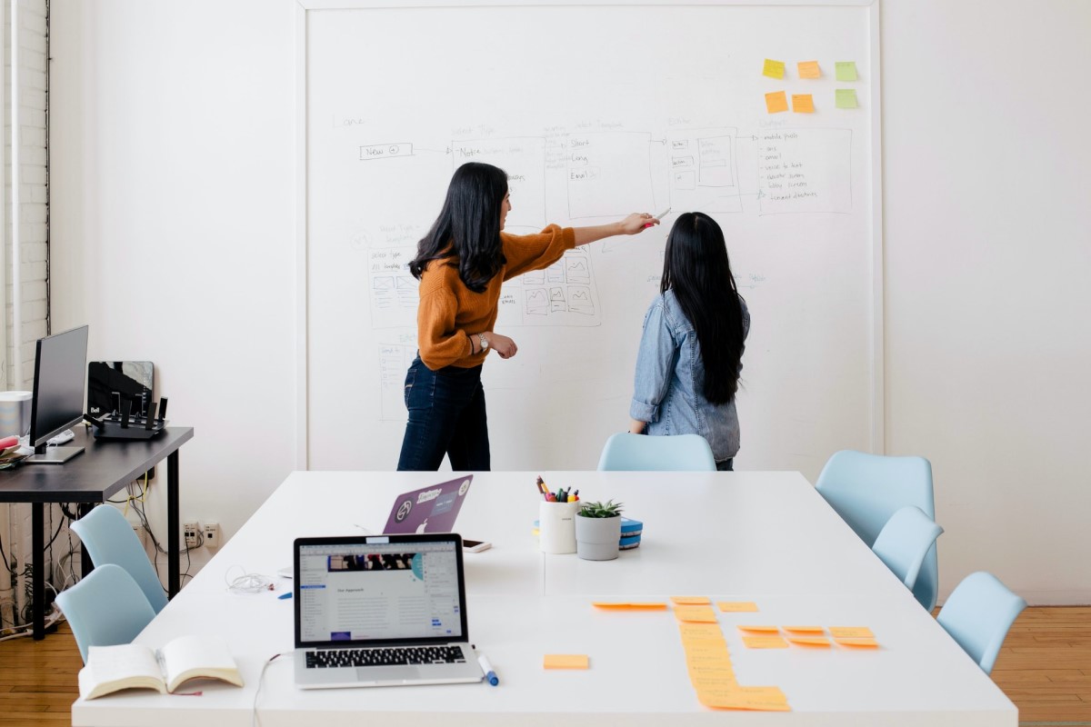 two women writing notes on a whiteboard