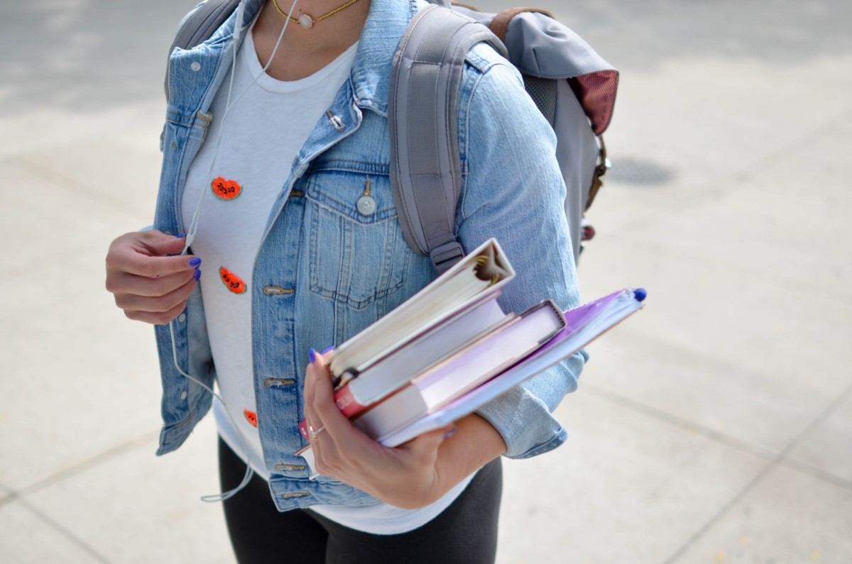 woman with headphones carrying books