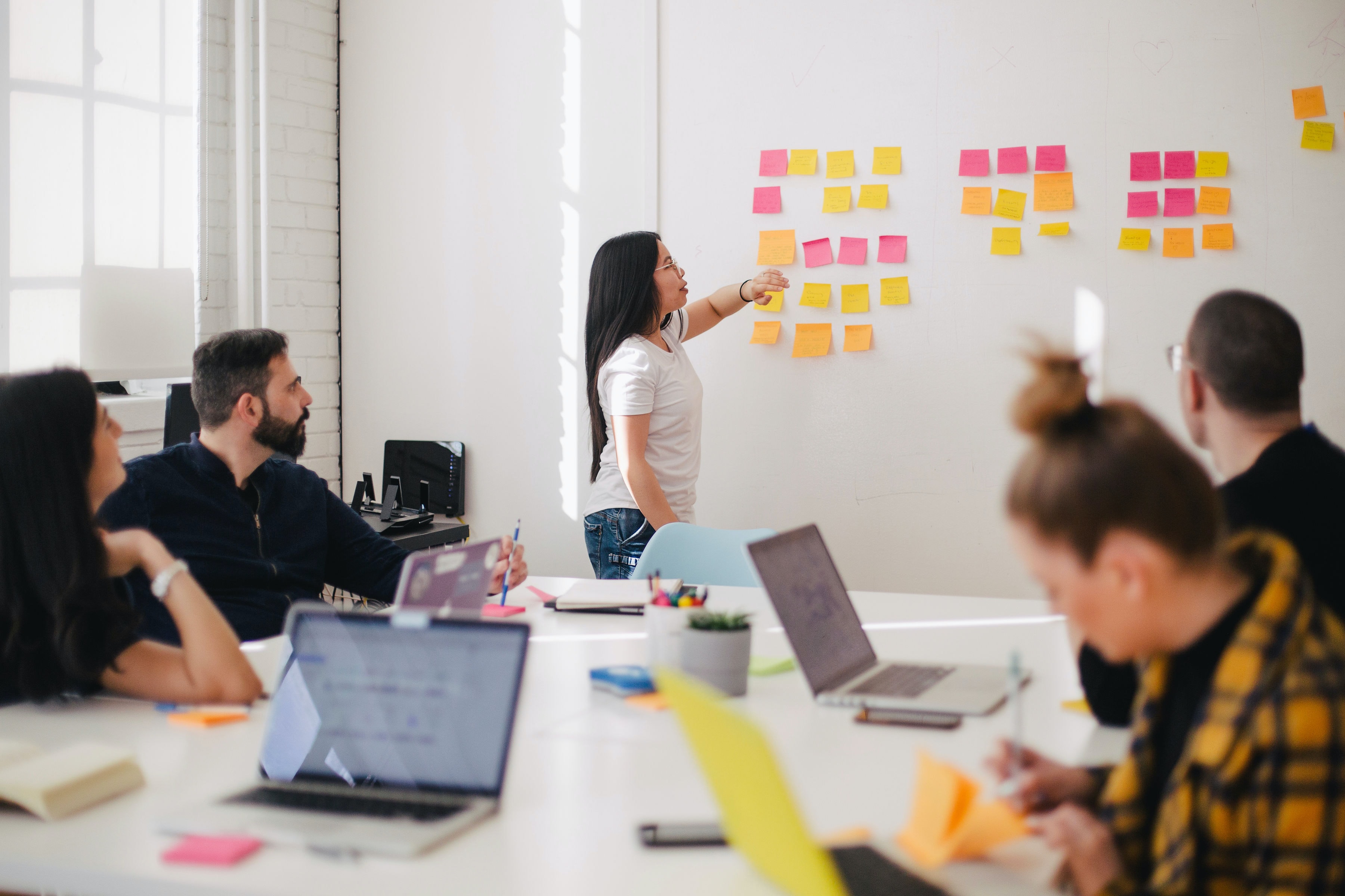 office meeting, woman putting post it notes on whiteboard