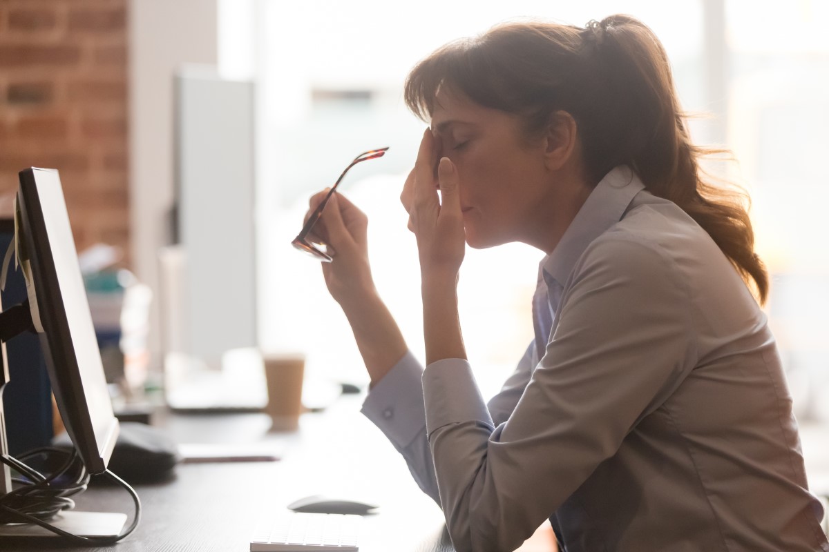 woman sitting in front of a computer, rubbing her eyes