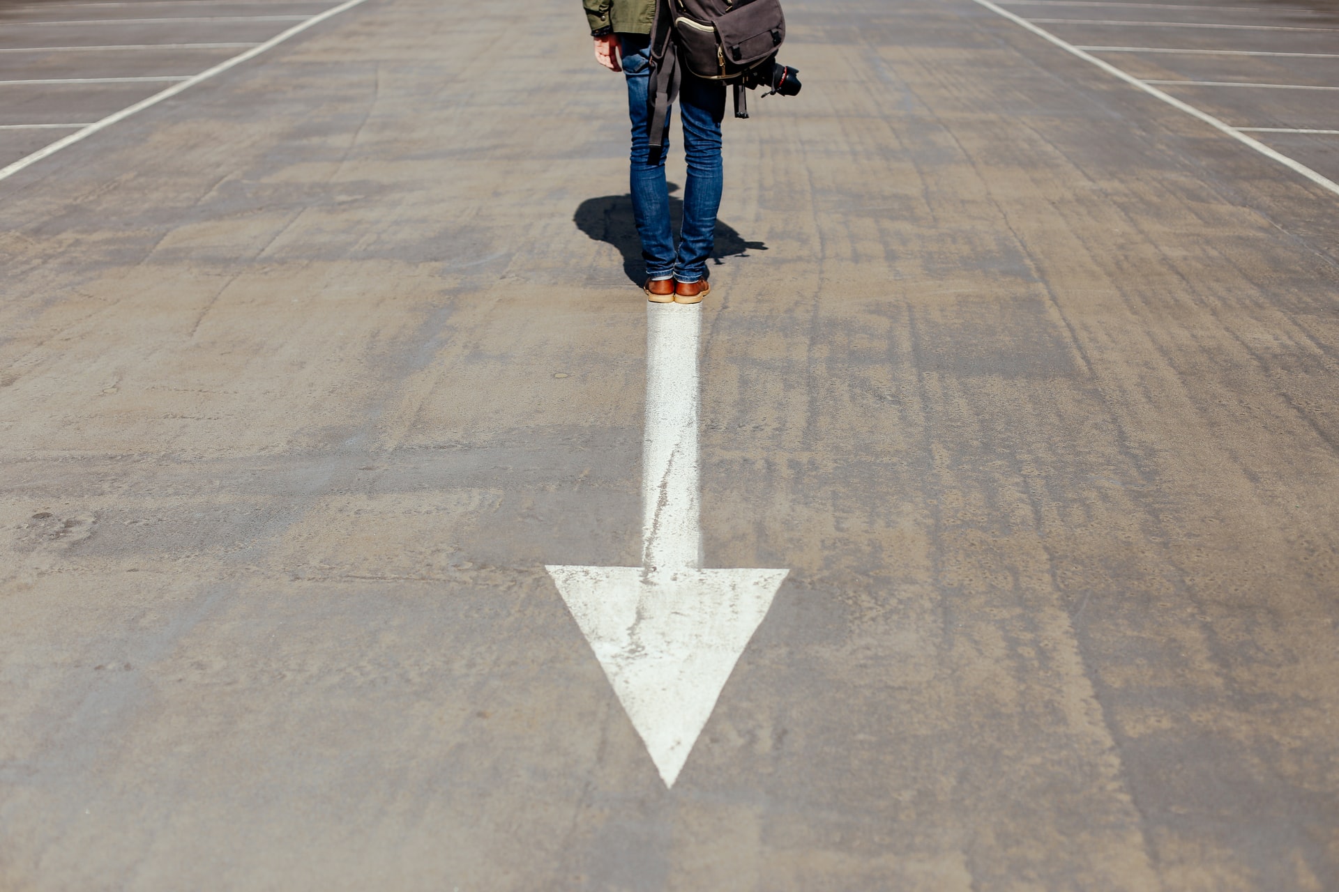 man standing on an arrow on the road