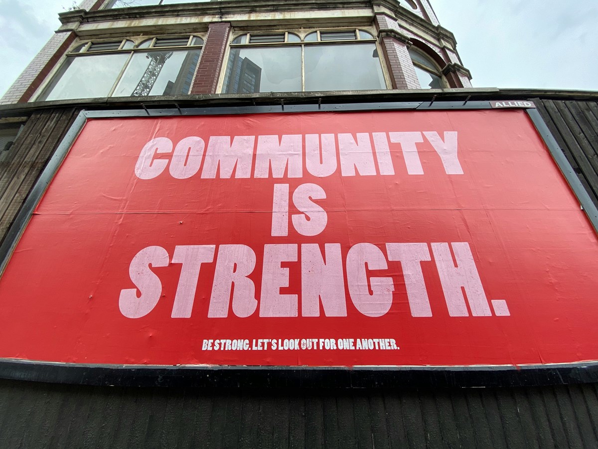 a street banner "community is strength. be strong. let's look out for one another."