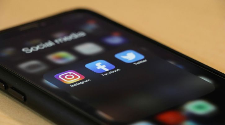 A mobile ohone showing social media icons for Instagram, Facebook and Twitter (before it became X)