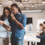 Two people standing in a coworking office looking at a mobile screen