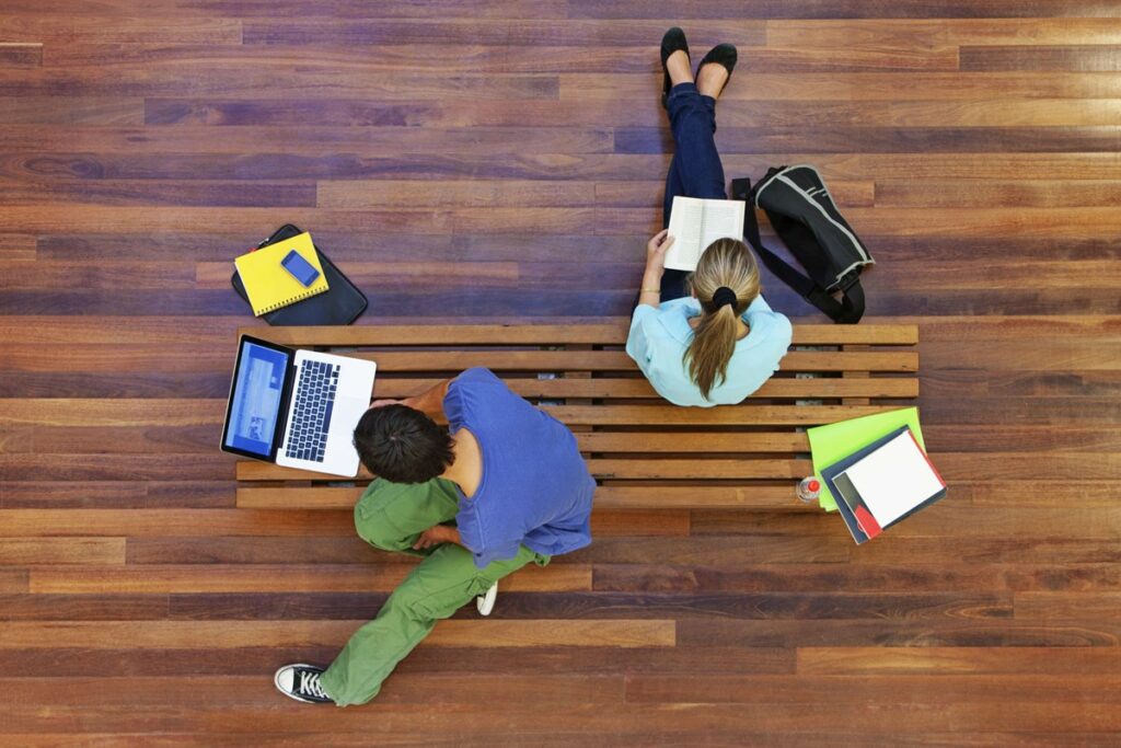 Photo of two people working on laptops on the floor, taken from above