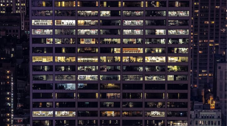 Exterior of a large office block in a city at night with lights on
