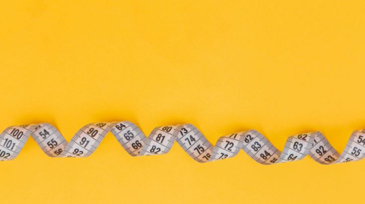 A tape measure unfurling against a bright yellow background