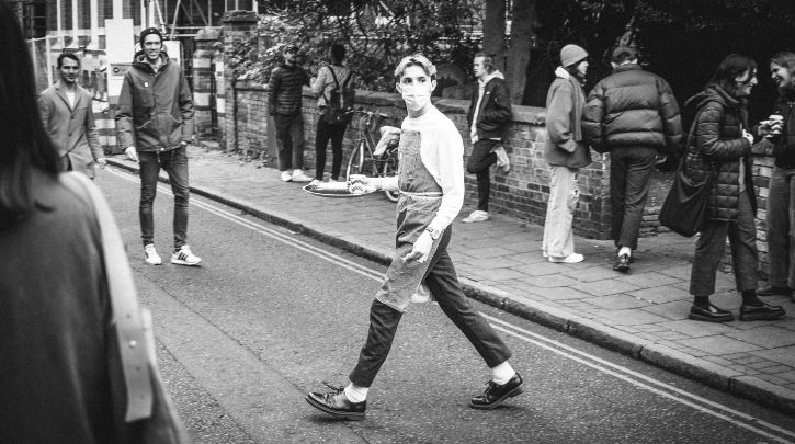 Man in the street with a face mask and apron holding a silver serving tray
