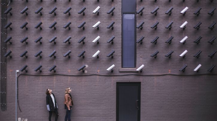 Two people looking up at a wall of CCTV cameras